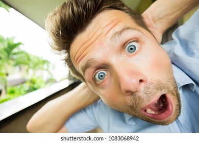 Panic man is shocked. His face is close to camera. He is opening his mouth in surprise. Concept of real man emotion