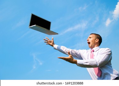 Panicked businessman reaching out to catch a laptop computer falling from blue sky - Powered by Shutterstock