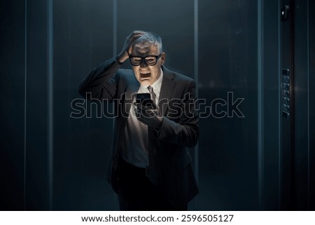 Panicked man stuck in the elevator, he is using the smartphone light and waiting