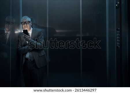 Panicked man stuck in the elevator, he is using the smartphone light and waiting
