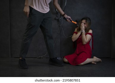 Panicky Woman In Red Being Tied, Psycho Killer Man Holding Hammer Threatening To Female Victim. Concept Of Women Victim, Violence, Hostage,crime