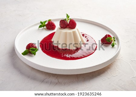 Panna cotta with raspberry syrup, pistachios, berries and mint, high key, close up