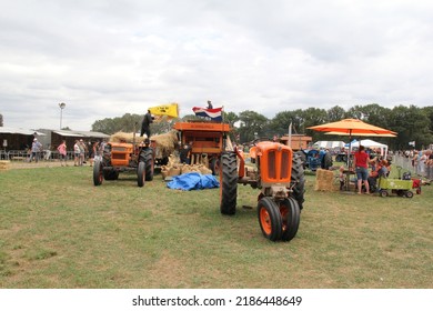 Panningen, Holland - jul 31, 2022: an old classic threshing machine and tractors are working in the field with wheat 