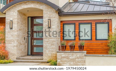 Pano Arched portico with stone brick wall and glass door at the entrance of a house. Facade of a beautiful house with balcony in the scenic neighborhood of Long Beach California.