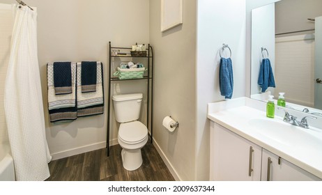 Pano Bathroom Interior With Over-the-toilet Storage Rack And Wooden Flooring