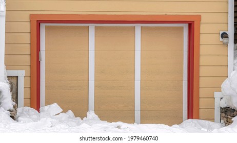 Pano Exterior Of An Attached Single Car Garage Of Home With Snowy Driveway In Winter. Wooden Stairs Leads To The Deck And Front Door Entrance.