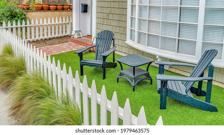 Pano Front Yard Of House With Furniture Against Curved Bay Window In Long Beach CA. Wall Cladding, Low Picket Fence, And Pathway Leading To The Entrance Can Also Be Seen At The Facade.