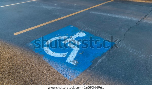Pano Handicapped parking space at a parking lot\
outside a building on a sunny\
day