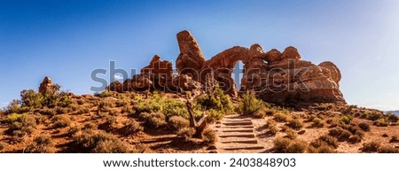 Panoram shot of steps to red sandstone arch, rock window and monolith in stone sculpture in arches national park in utah, america, usa