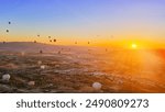 Panorama aerial landscape of Goreme valley with colourful hot air balloons flying high in the morning at beautiful sunrise sunlight above mountains and green trees of Turkey geological national park