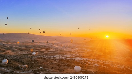 Panorama aerial landscape of Goreme valley with colourful hot air balloons flying high in the morning at beautiful sunrise sunlight above mountains and green trees of Turkey geological national park - Powered by Shutterstock