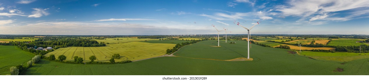 Panorama aerial view of countryside infrastructure windmills, agriculture fields, plant and farm. Agriculture fields and different variety of harvest, from the air perspective, Germany, Europe.
