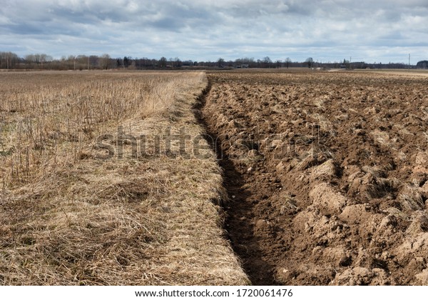 Panorama of arable\
land under amazing clouds, countryside in early spring. \
Preparatory agricultural work. furrow divides soil in two parts\
plowed field and dry stubble\
meadow