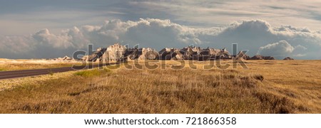 Panorama of badlands national park with vista of mountain range with large clouds in background