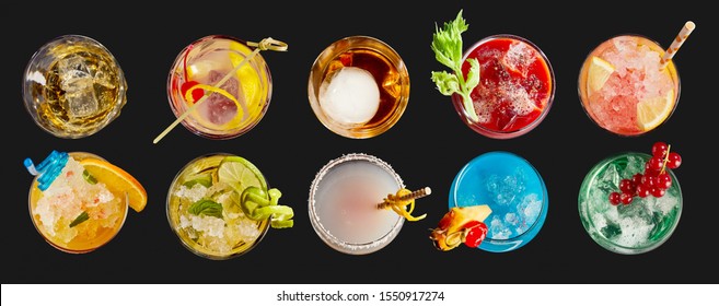 Panorama banner with an assortment of colorful exotic alcoholic cocktails served in glasses with garnishes viewed in two neat lines top down on black