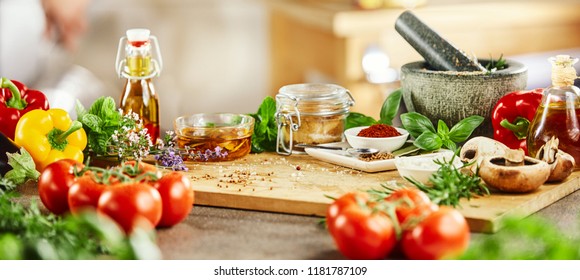 Panorama banner with fresh culinary herbs and spices on a chopping board with a pestle and mortar surrounded by fresh vegetables for salads - Powered by Shutterstock