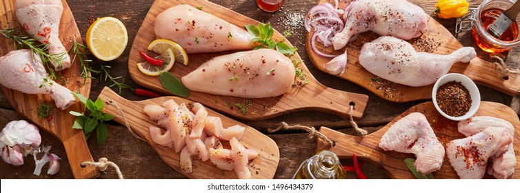 Panorama banner of raw chicken portions for cooking and barbecuing with skinless breasts and diced strips for goulash or stir fry with legs and wings with skin viewed from above with fresh seasoning