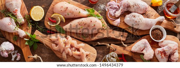 Panorama banner of raw chicken portions for\
cooking and barbecuing with skinless breasts and diced strips for\
goulash or stir fry with legs and wings with skin viewed from above\
with fresh seasoning