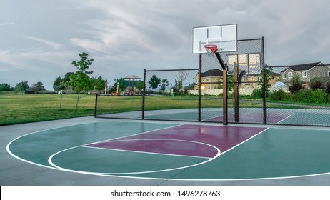 Panorama Basketball Courts At A Park Near Multi Storey Family Homes Under Cloudy Sky