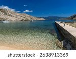 Panorama of the bay with the Vela Luka beach below, view of the beach from the top of the mountain, rocky trail leading to the picturesque beach



