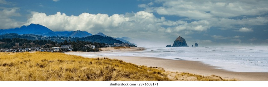 Panorama of Beach grass and Haystack Rock and city of Canon Beach, Oregon