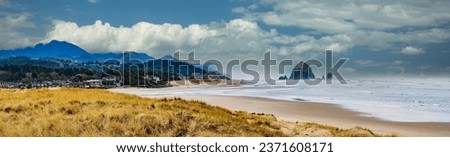 Panorama of Beach grass and Haystack Rock and city of Canon Beach, Oregon