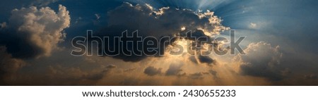 Panorama Beautiful light Sun shines behind the cumulus clouds.Colorful sunrise with Clouds over hill.Sun hiding behind a cloud on the day sky.Sunray with dark Clouds sunset.