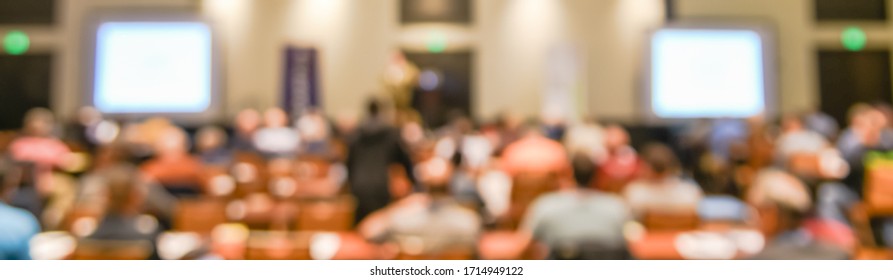 Panorama Blurred Crowd Of Diverse People Attend Investing Workshop At Hotel Conference Room In Dallas, Texas, America. Motion Blurry Classroom With Large Projector Monitor, Students And Speaker