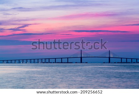 Panorama of bright sunrise lighting up the sky behind Sunshine Skyway Bridge from St Petersburg Florida across Tampa Bay.