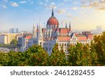 Panorama with Budapest Hungarian Parliament building at Danube river in city, Hungary. Scenic summer panoramic view. Green trees and blue dramatic sky clouds. Europian capital city