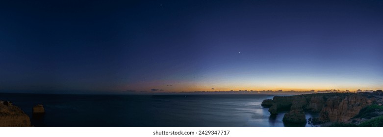 Panorama of cliffs at the coast of Atlantic Ocean during dusk with planets Venus, Saturn and Jupiter near the Cave of Benagil, Algarve, Portugal - Powered by Shutterstock