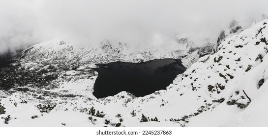 Panorama in the clouds at the Black Caterpillar Pond . Polish Tatra Mountains in winter aura with lots of snow.