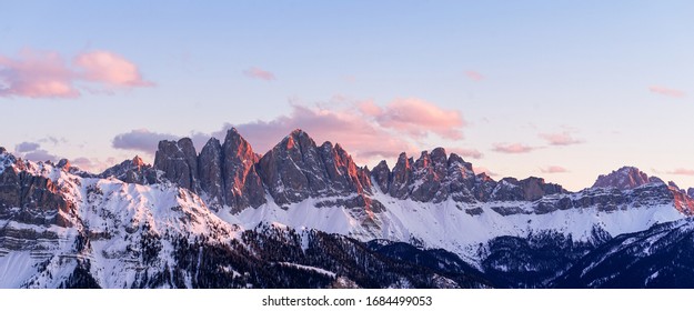 Panorama of a colored winter mountain landscape in South Tyrol, Italy during sunset in winter with the snow covered Seceda mountains.
