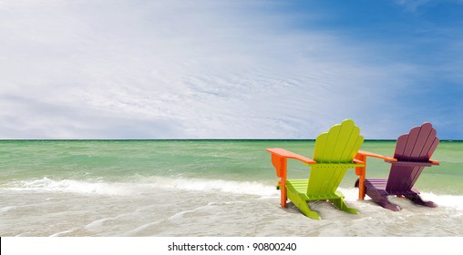 Panorama of colorful lounge chairs at a tropical beach in Miami Florida. Beautiful aqua green waters of the ocean and a blue sky  with clouds in the background
