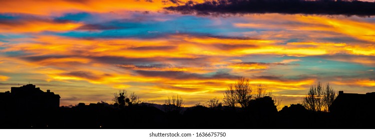 Panorama of colorful sunset sky over the silhouettes of houses in the city