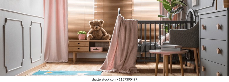 Panorama Of A Cozy, Gray Nursery Bedroom Interior With A Classic Wooden Baby Crib And Pastel Pink Decorations