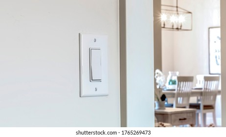 Panorama crop Wall mounted electrical rocker light switch with blurry dining room background