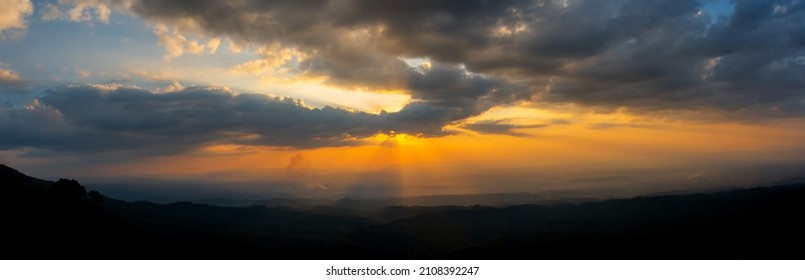 Panorama Dark cloud sunset over Dark mountain.Colorful sunrise with Clouds over hill.Sun hiding behind a cloud on the day sky. - Powered by Shutterstock