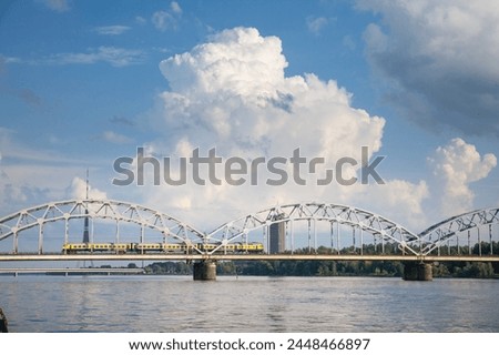 Panorama of the Daugava river in Riga, latvia, with a train from Latvian railways over dzelzcela tilts or Riga Railway Bridge with a skyline of business skyscrapers in background with high rise towers
