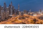 Panorama of Dubai Marina and media city highway intersection spaghetti junction day to night transition after sunset. Illuminated tallest skyscrapers on a background. Aerial top view from JLT district