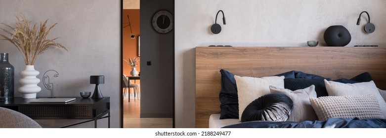 Panorama of elegant bedroom with cozy bed with wooden headboard, mirror in black frame and decorated desk
