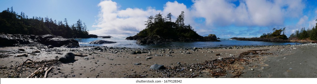 Panorama of empty Canadian west coast beach with rocky islands, waves, sand and trees