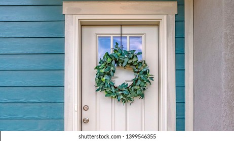 Panorama Facade Of A Home With A Simple Leafy Wreath Hanging On The White Front Door