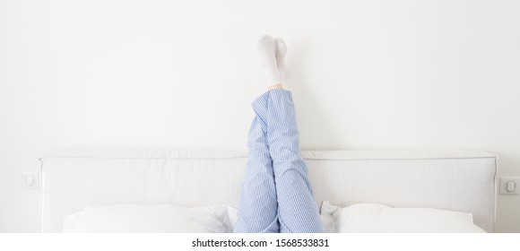 Panorama Of Female Legs Raised Up High Lying On Bed In Bedroom