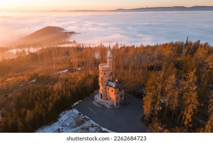 Panorama of foggy landscape at Goethe's Lookout Tower in Karlovy Vary, Bohemia, Czech Republic. Misty clouds over the forest. View below of the fairytale landscape. Misty forest hills. Sunset 