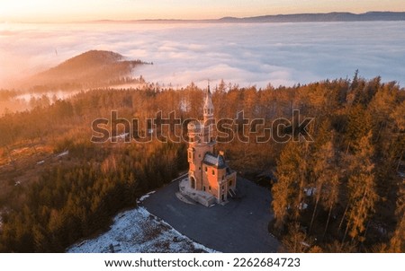 Panorama of foggy landscape at Goethe's Lookout Tower in Karlovy Vary, Bohemia, Czech Republic. Misty clouds over the forest. View below of the fairytale landscape. Misty forest hills. Sunset 