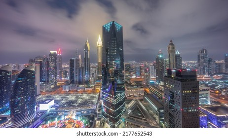 Panorama Of Futuristic Skyscrapers After Sunset In Financial District Business Center In Dubai On Sheikh Zayed Road Day To Night Transition Timelapse. Aerial View From Above With Cloudy Sky