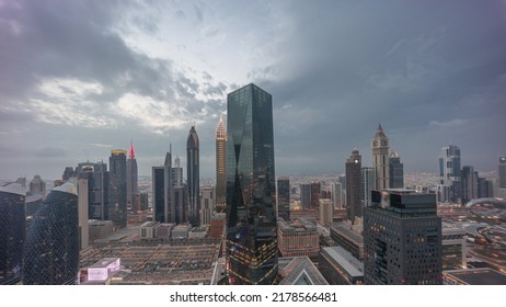 Panorama Of Futuristic Skyscrapers After Sunset In Financial District Business Center In Dubai On Sheikh Zayed Road Day To Night Transition Timelapse. Aerial View From Above With Cloudy Sky