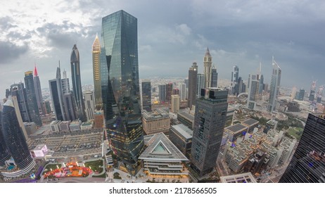 Panorama Of Futuristic Skyscrapers After Sunset In Financial District Business Center In Dubai With Traffic On A Road Day To Night Transition Timelapse. Aerial View From Above With Cloudy Sky