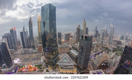 Panorama Of Futuristic Skyscrapers After Sunset In Financial District Business Center In Dubai With Traffic On A Road Day To Night Transition Timelapse. Aerial View From Above With Cloudy Sky